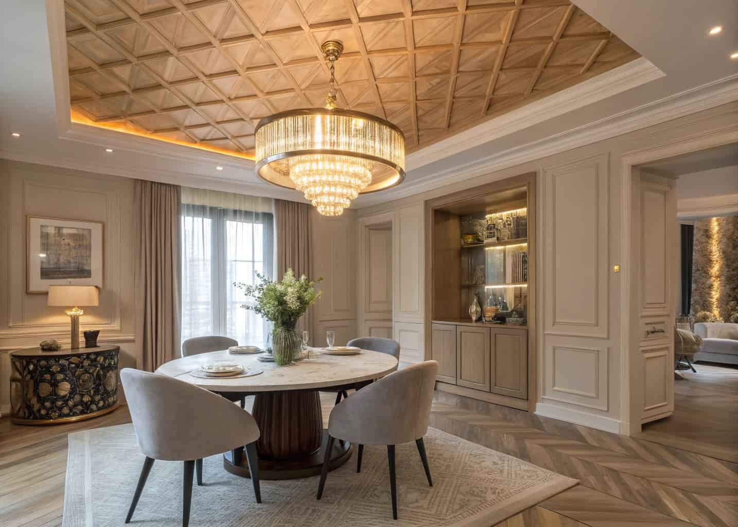 An elegant dining room with a herringbone patterned natural wood ceiling, gold pendant chandelier, round dining table, neutral interior palette, soft warm lighting, luxury home interior photo.